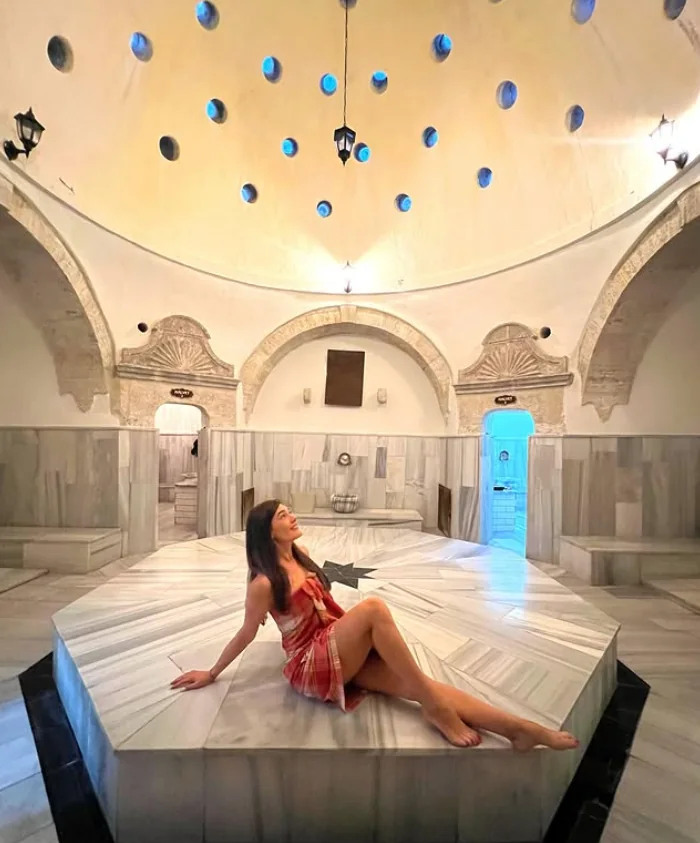 Guest seated on the göbek taşı beneath the domed hot room of Ürgüp Hamam.