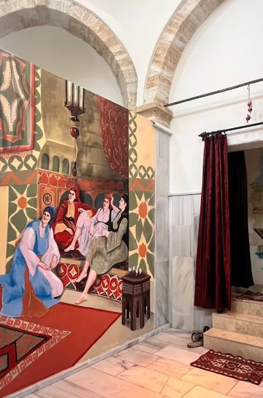 Historical hammam mural, stone arches and marble wall panels inside Ürgüp Hamam.