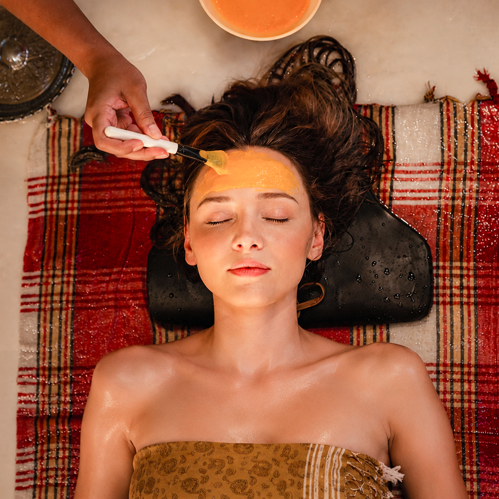 Guest receiving a nourishing face mask during a hammam ritual.