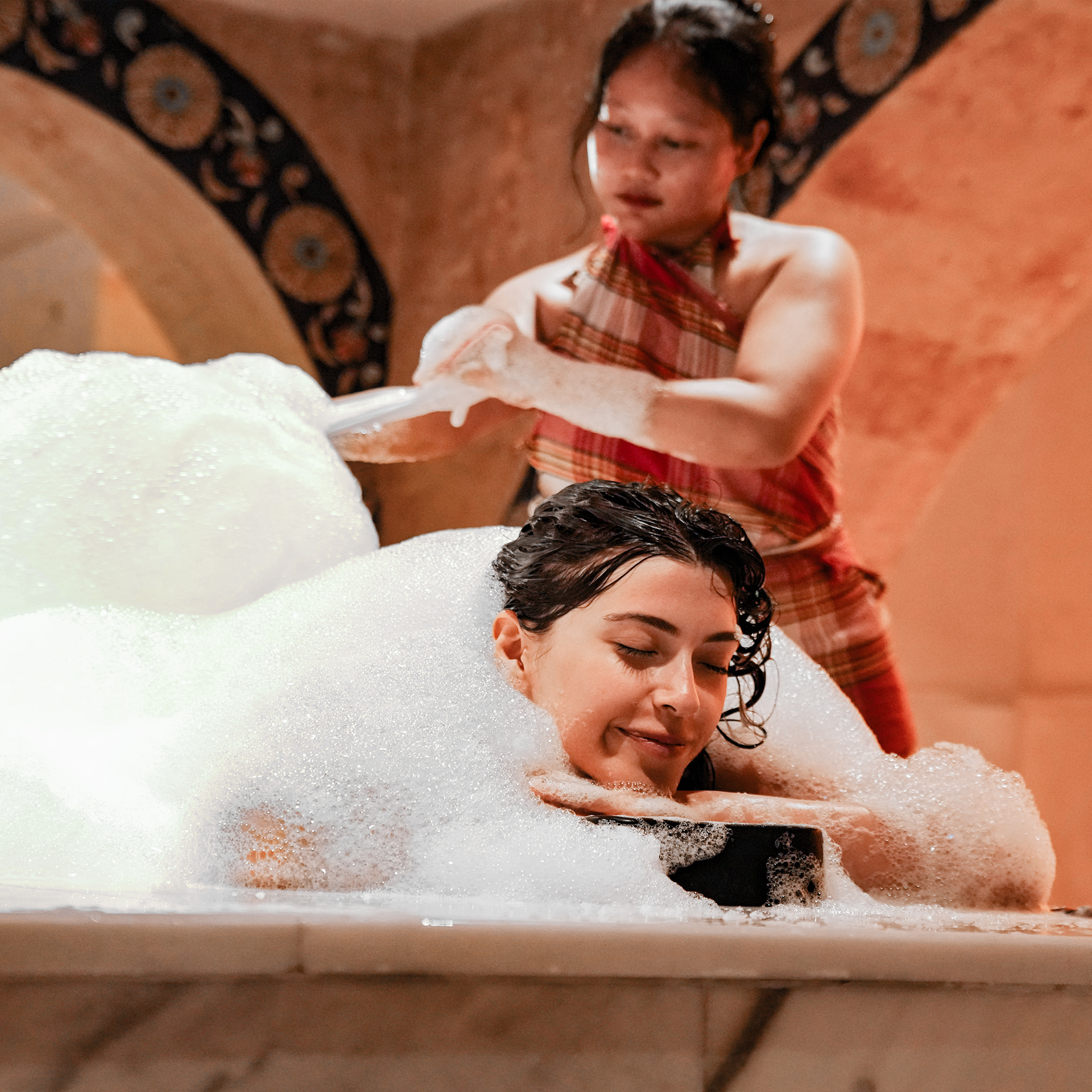 Guest immersed in abundant foam during the private Sultan hammam ritual.