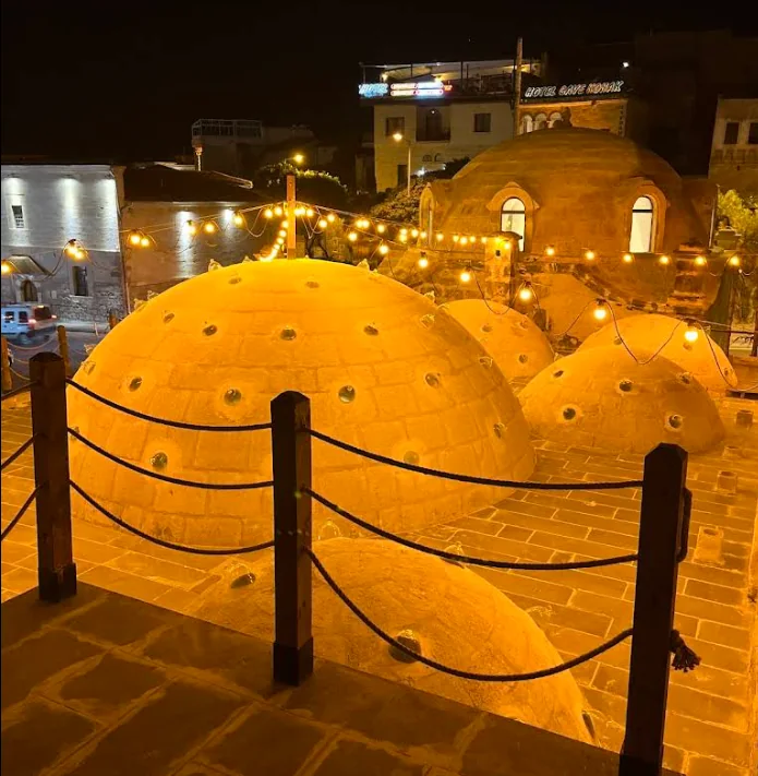 The illuminated stone domes and circular roof lights of Ürgüp Hamam at night.