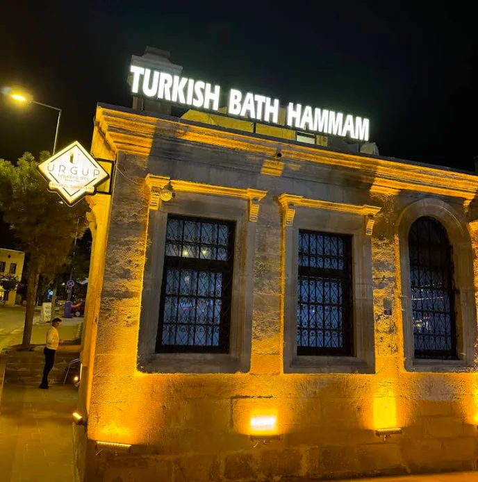 Illuminated stone façade of Ürgüp Hamam beneath the Turkish Bath Hammam sign.