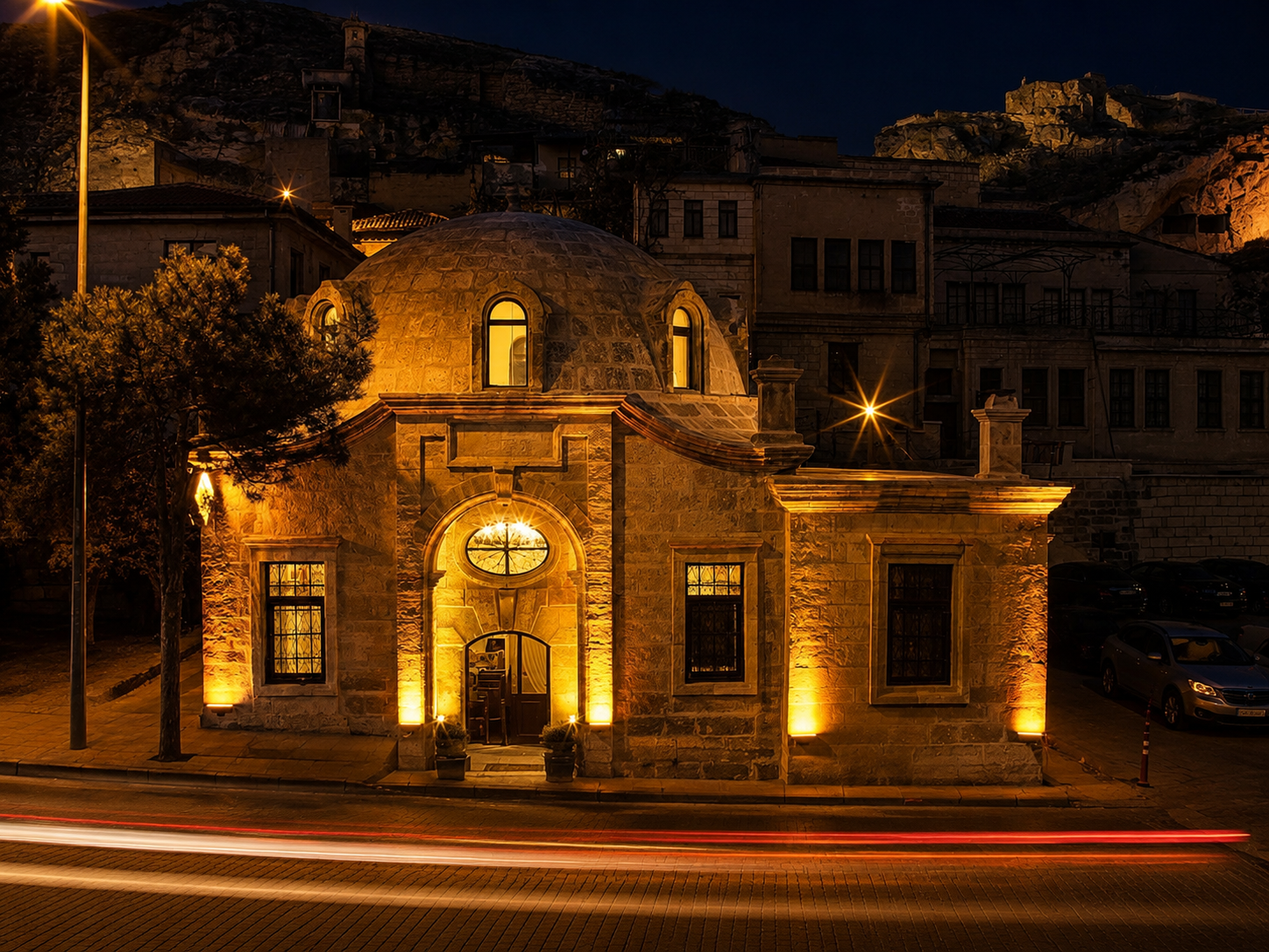 Front view of Ürgüp Hamam illuminated at night beneath the Cappadocia rock formations.