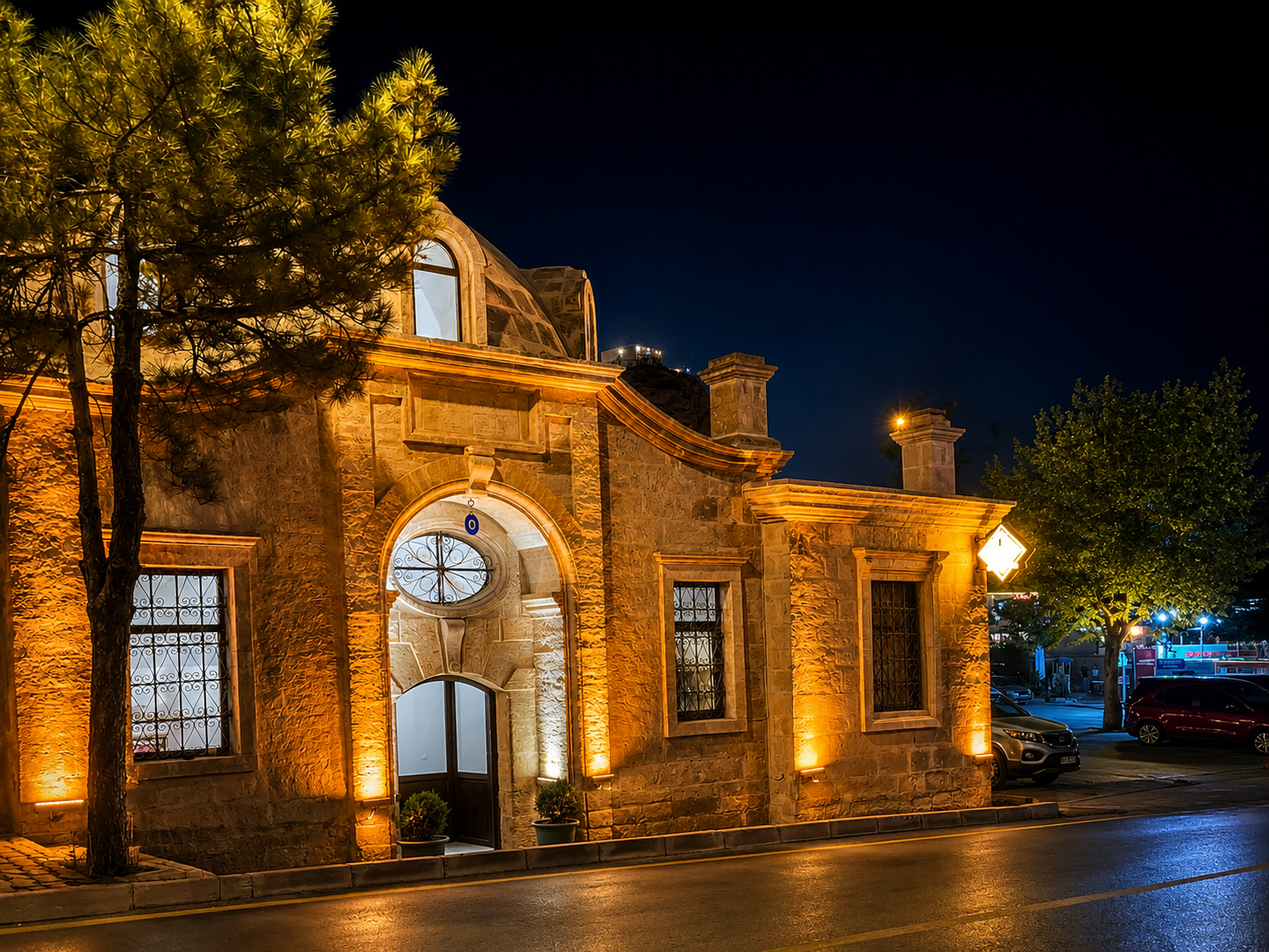 Historic stone façade and domes of Ürgüp Hamam seen from İstiklal Caddesi after dark.