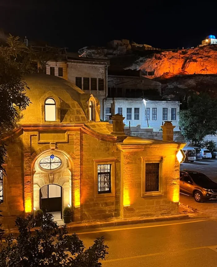 Ürgüp Hamam illuminated at night with the rocky Temenni Hill rising behind it.