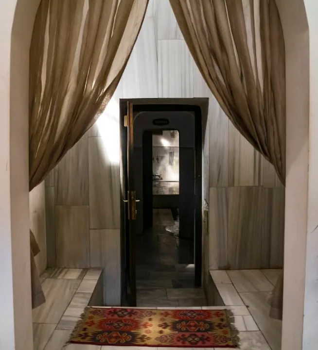 Curtained stone arch framing the passage between the warm and hot rooms of Ürgüp Hamam.